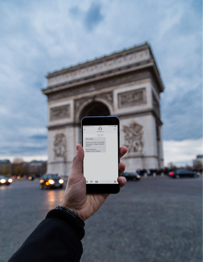 Telefon med SMS på skærmen foran Triumfbuen i Paris