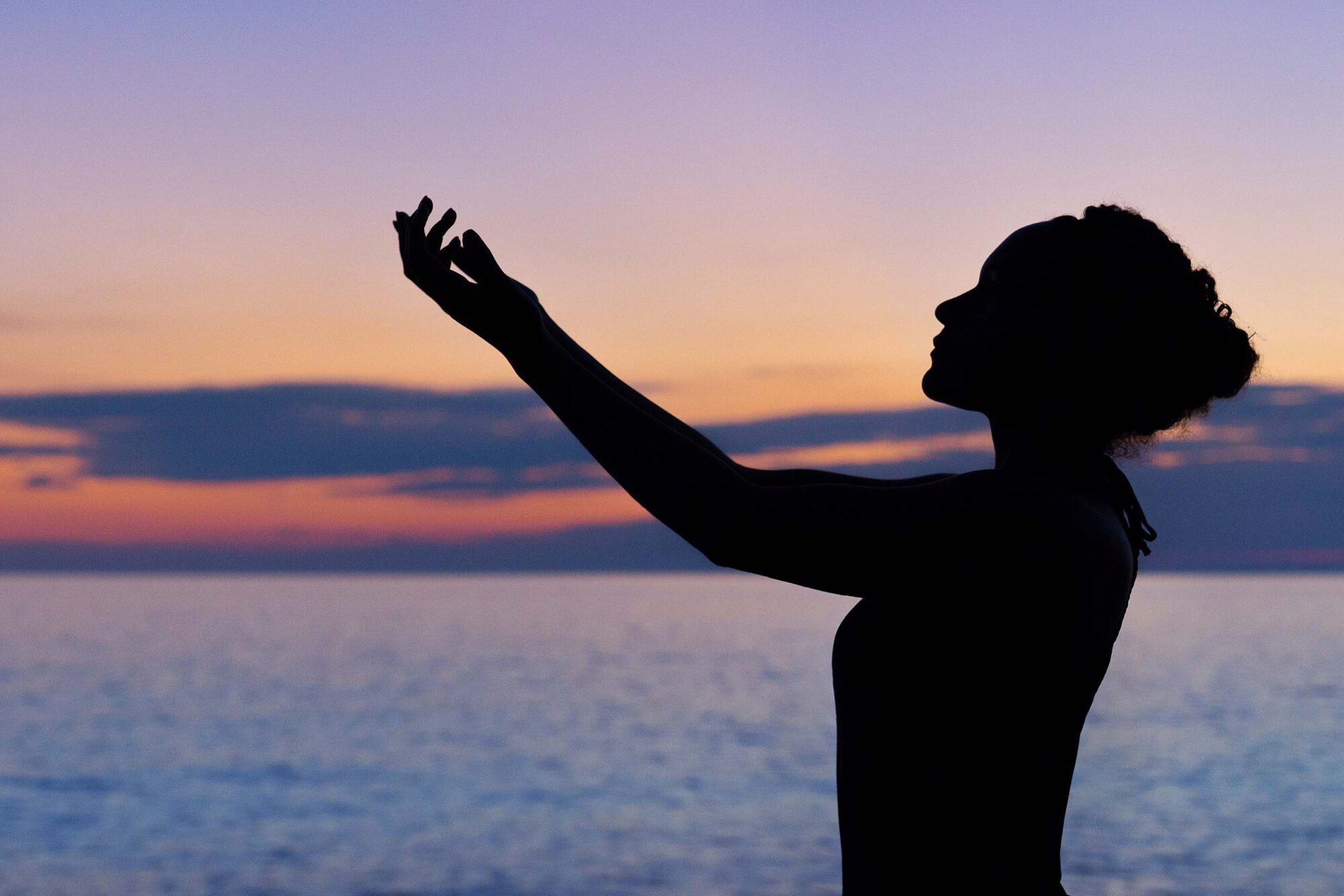 Kvinde der laver yoga foran farvet horisont