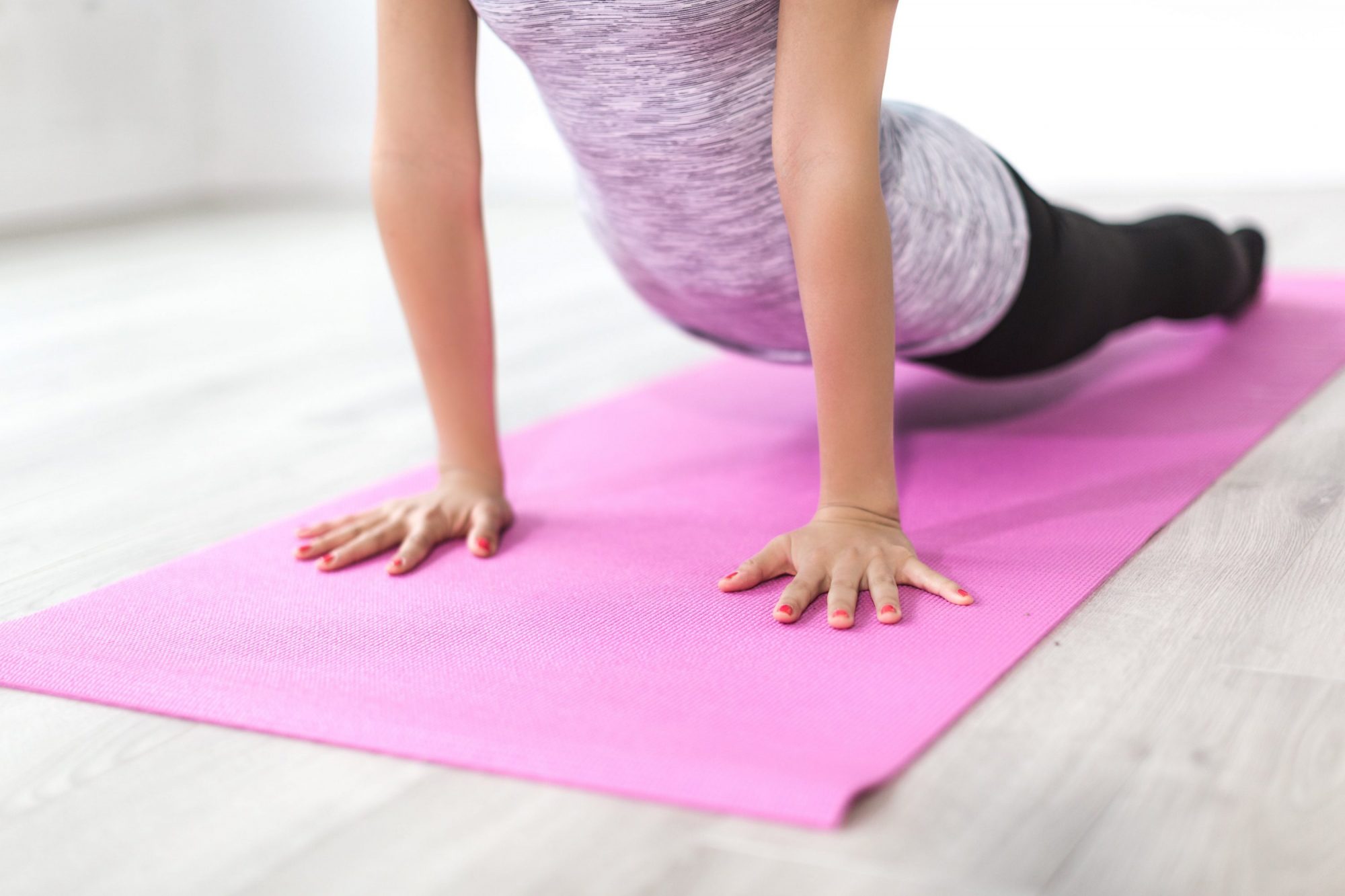 Kvinde der udfører yogaposition på yogamåtte