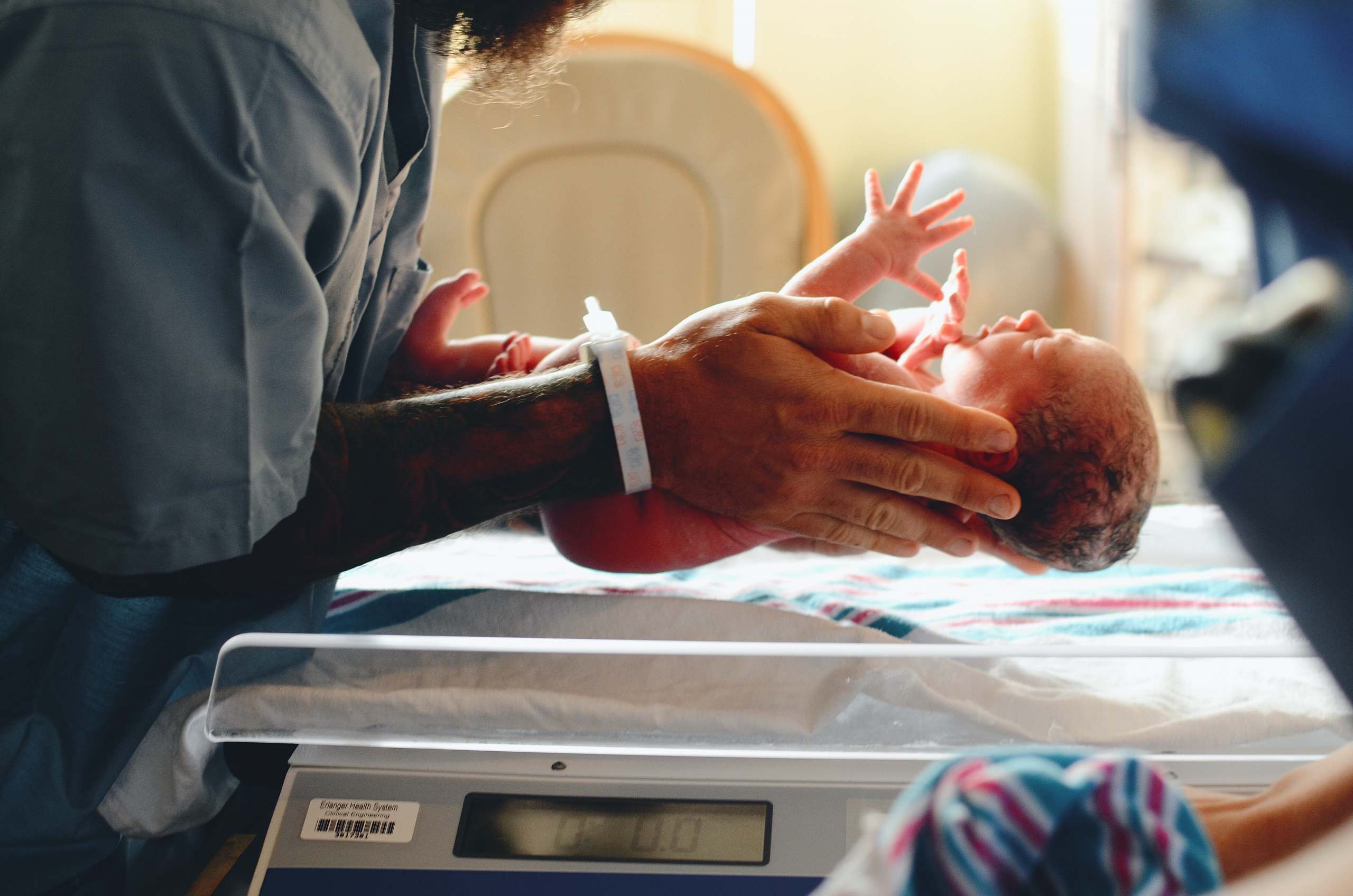En sygeplejerske der vejer et spædbarn lige efter fødsel