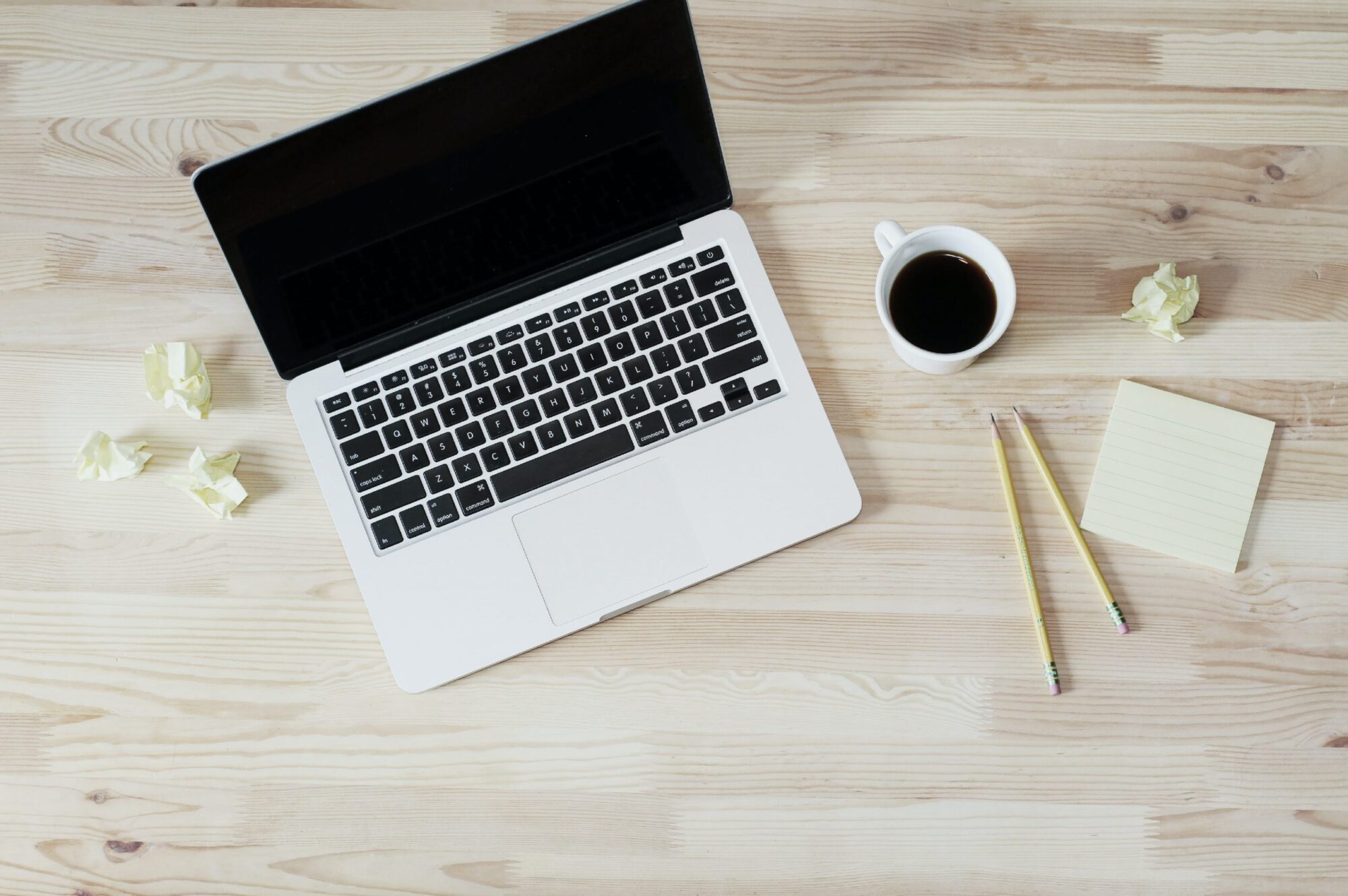 laptop med kop kaffe ved siden af på et skrivebord af træ