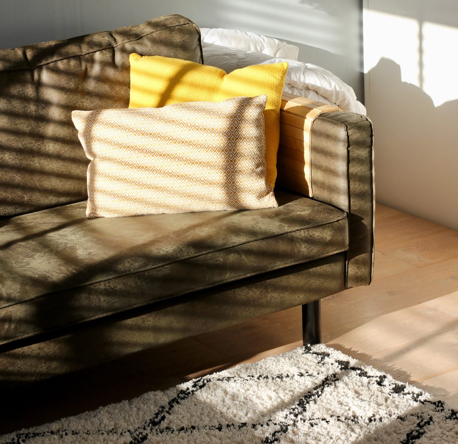 Komfortabel sofa med dekorative puder i solskin