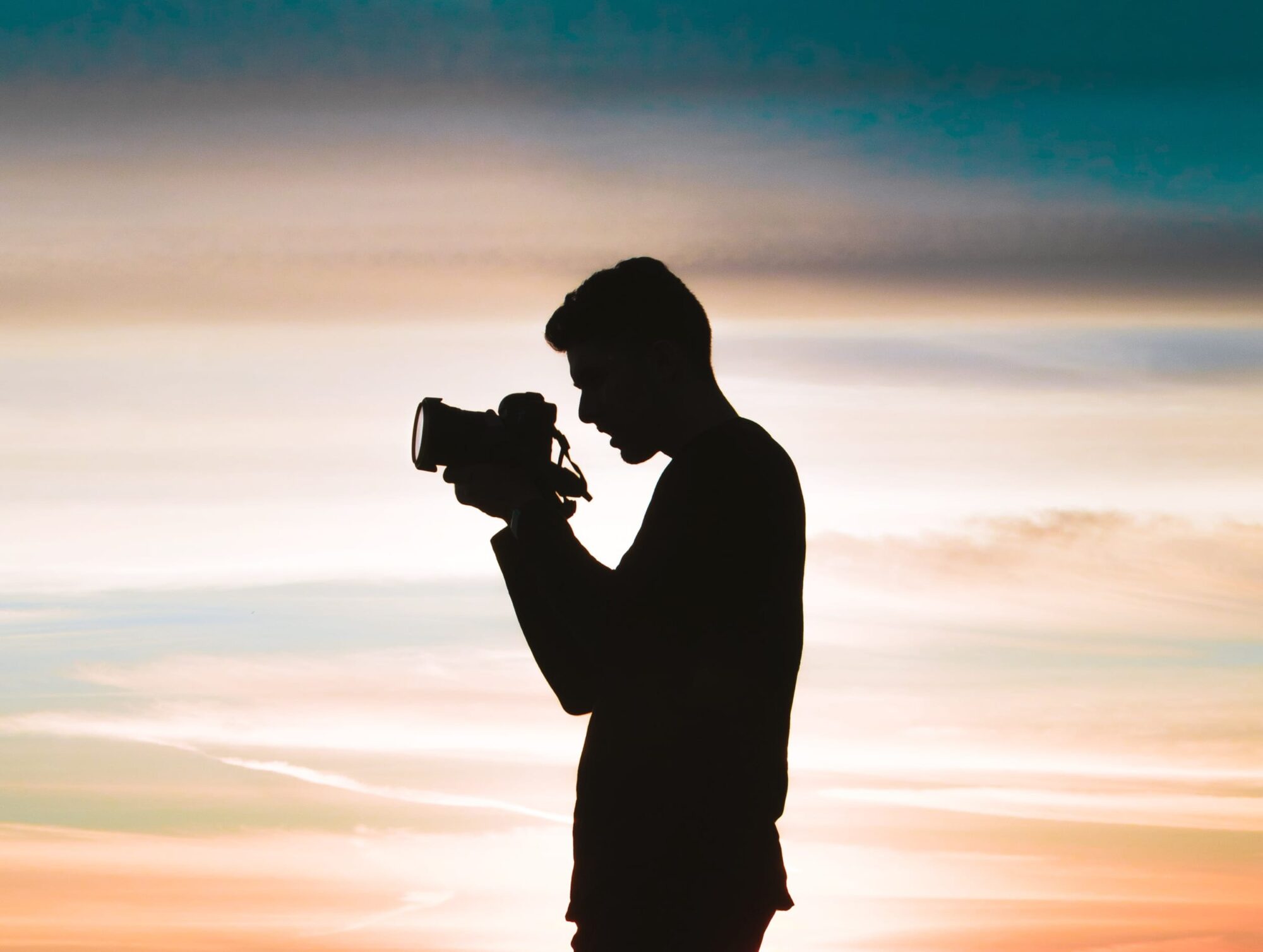 Silhouet af mand der tager billede ved solnedgang
